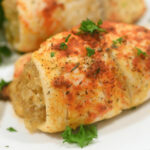 Twice-baked potatoes stuffed with crabmeat and garnished with parsley on a white plate.