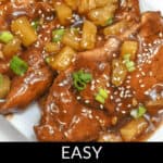 A plate of Slow Cooker Honey Garlic Chicken garnished with sesame seeds, pineapple chunks, and sliced green onions. Text overlay reads "EASY CROCKPOT GARLIC HONEY CHICKEN.