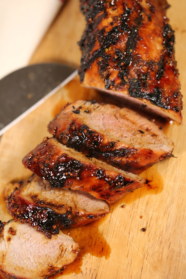Grilled Pork tenderloin sliced on a wooden cutting board