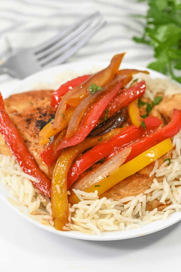 A white plate with balsamic chicken and peppers.
