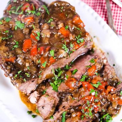 Slow cooker italian beef on a white plate with a checked napkin and silverware