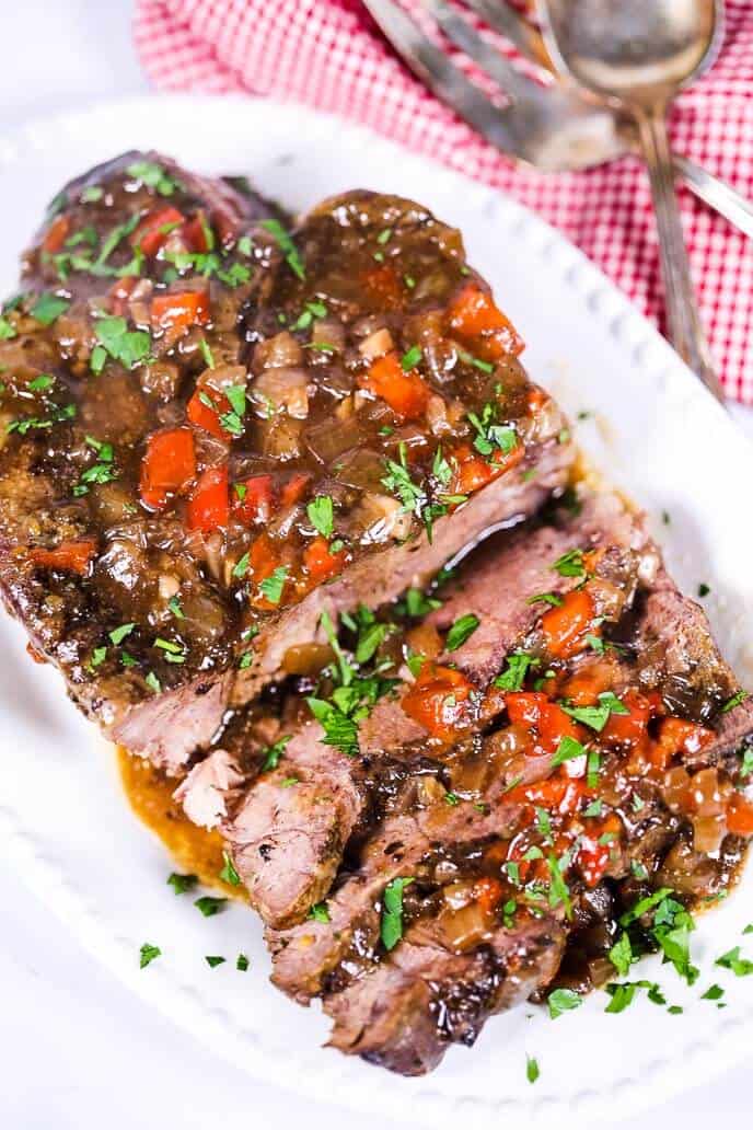 Slow cooker italian beef on a white plate with a checked napkin and silverware