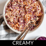 A bowl of creamy Southern coleslaw made with shredded cabbage and carrots, accompanied by a fork and spoon. A checkered cloth and a small bowl of purple cabbage are nearby. Text reads "Creamy Southern Coleslaw Recipe.