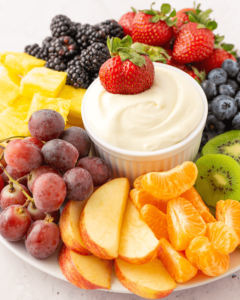 A colorful selection of fresh fruits with a bowl of marshmallow fluff fruit dip.