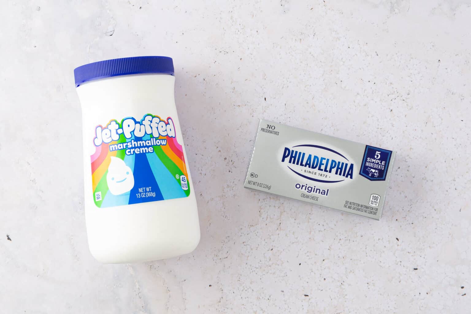 A jar of jet-puffed marshmallow fluff and a package of Philadelphia original cream cheese on a light background, perfect for fruit dip.