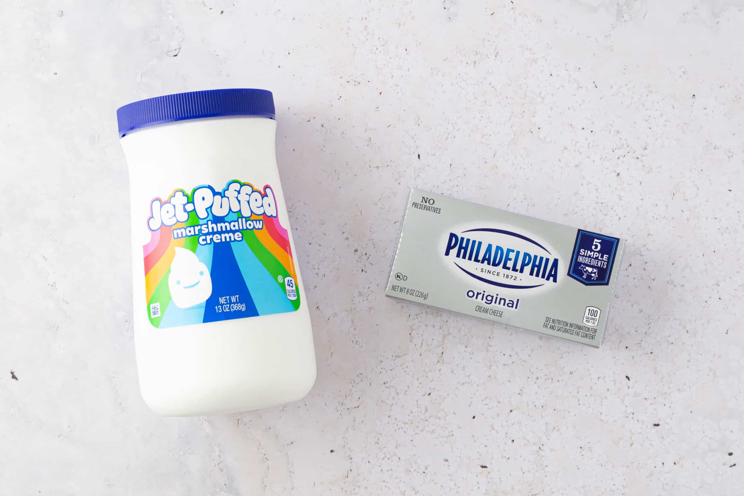 A jar of jet-puffed marshmallow fluff and a package of Philadelphia original cream cheese on a light background, perfect for fruit dip.