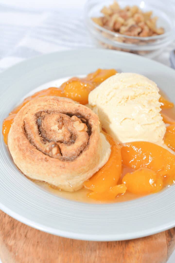 A dish of peach cobbler with ice cream.