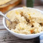A white bowl of Chicken Cobbler with a spoon in it.