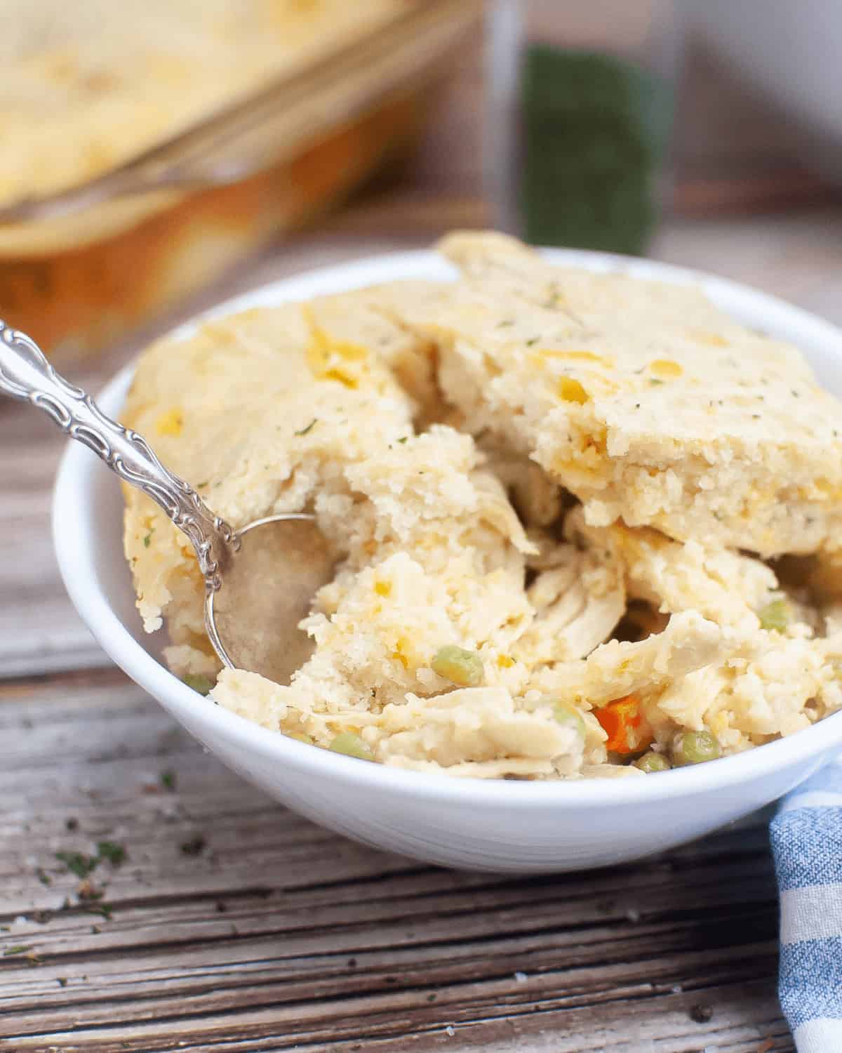 A white bowl of Chicken Cobbler with a spoon in it.