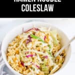 A bowl of ramen noodle coleslaw with shredded cabbage, green onions, and broken ramen noodles sits on a white surface next to a cloth napkin and fork—a perfect depiction of a delicious Ramen Noodle Salad Recipe.