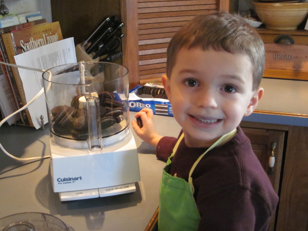 Child putting Oreo cookies in a food processor. 