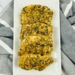 Creamy Pan seared pork chops with herbs on a white plate.