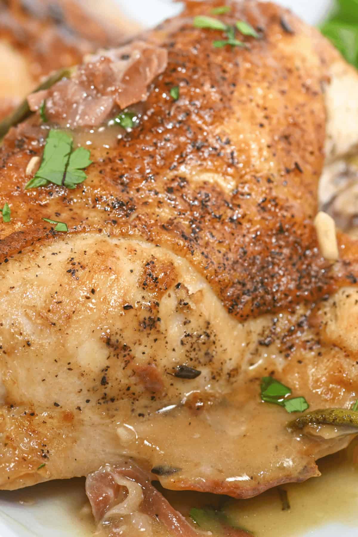 Close-up of a seasoned and cooked Herbed Lemon Chicken breast with herbs and a creamy sauce.