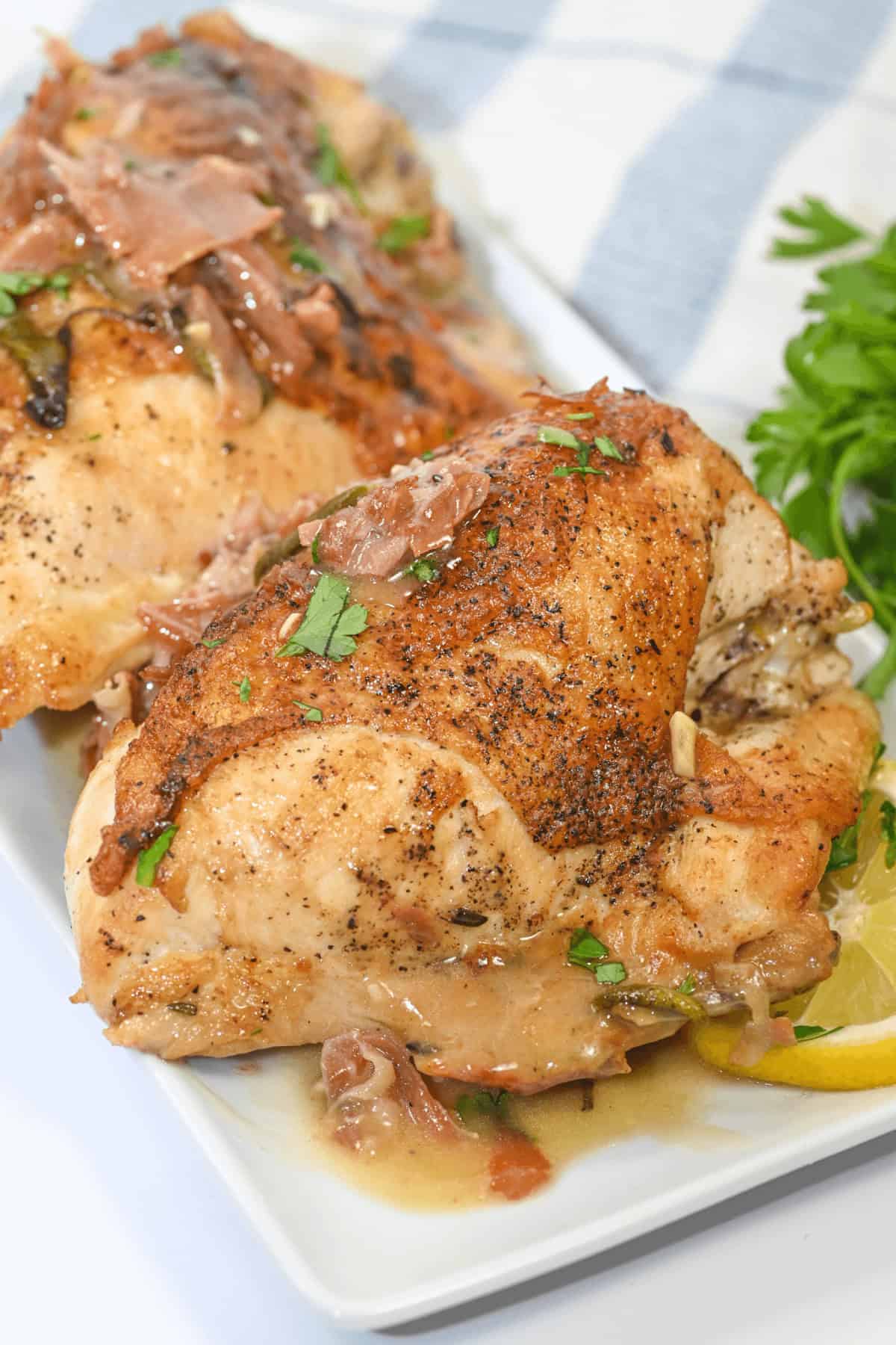 Herbed Lemon Chicken: Two pieces of roasted chicken garnished with herbs on a white plate, accompanied by lemon slices and parsley.