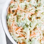 A bowl of creamy broccoli coleslaw with shredded carrots, cabbage, and fresh broccoli.