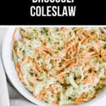A bowl of broccoli coleslaw with shredded carrots and onions, mixed in a creamy dressing, labeled "Tangy Broccoli Coleslaw.