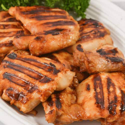 A white platter of Asian grilled chicken.