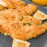 Chicken fillets on a blue plate with lemon slices.