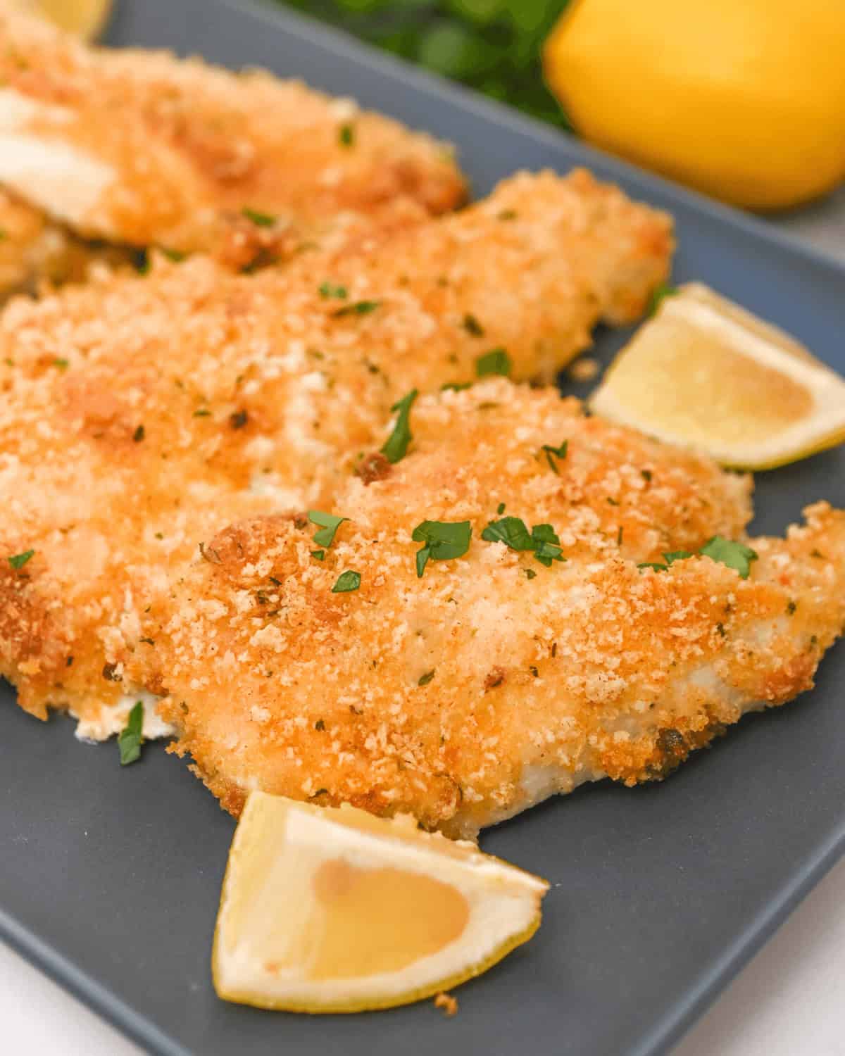 Chicken fillets on a blue plate with lemon slices.