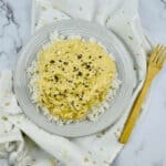 A glass bowl of the finished meal with a serving spoon beside it.