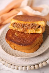Sloppy joe grilled cheese on a white place with peach napkin