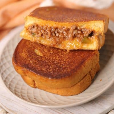 Sloppy joe grilled cheese on a white place with peach napkin
