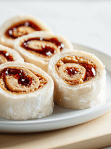 A plate of Peanut Butter and Jelly Pinwheel Sandwiches (PBJ Sushi) on a table.
