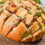 A side view of the stuffed bread with herbs and bacon on top.