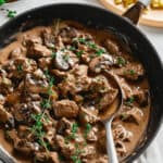 Venison stroganoff in a skillet with mushrooms and pasta.