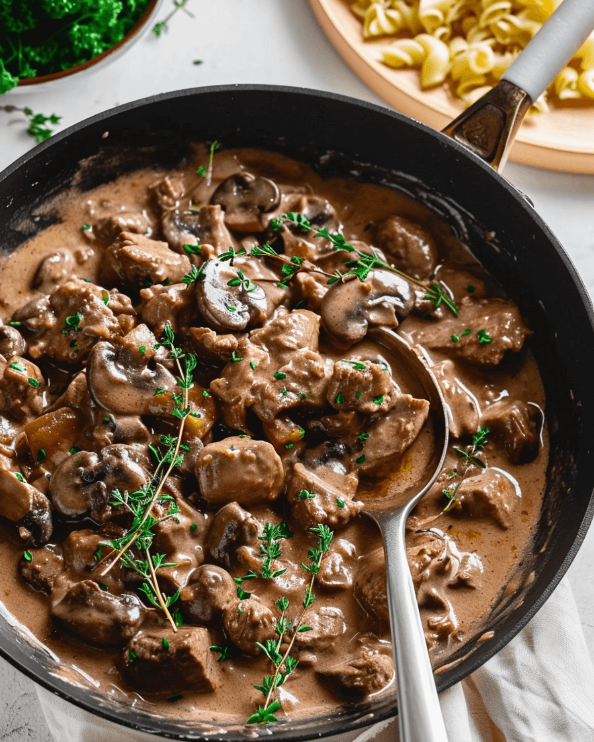 Venison stroganoff in a skillet with mushrooms and pasta.