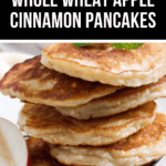 A delightful stack of whole wheat apple cinnamon pancakes graces the plate, crowned with a mint leaf and accompanied by fresh apple slices on the side.