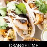 A close-up of succulent Halibut Fish Tacos, adorned with fresh cilantro and a dollop of cream, served alongside zesty lime wedges and a tangy dipping sauce, promises a delightful culinary experience.