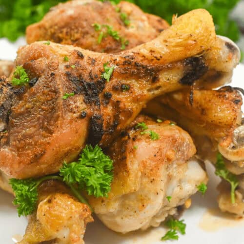 A stack of spicy roasted chicken legs on a white plate.