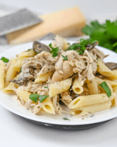 A plate of Slow Cooker Chicken Pasta with mushrooms and parsley.