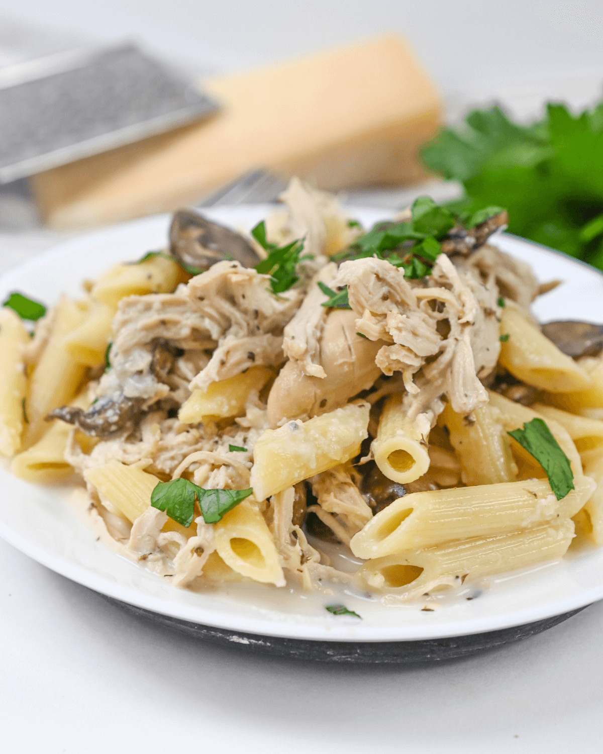 A plate of Slow Cooker Chicken Pasta with mushrooms and parsley.