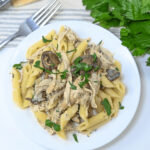 Slow Cooker Chicken Pasta with mushrooms and parsley on a white plate.