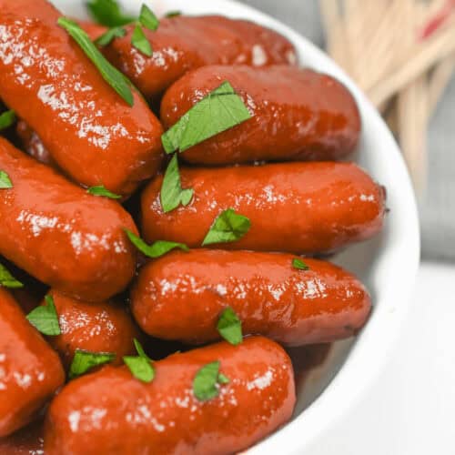 Crockpot lil smokies garnished with parsley in a white bowl.