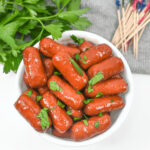 Crock pot lil smokies recipe served in a bowl with parsley and matchsticks.