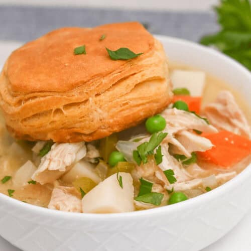 A scrumptious crock pot chicken pot pie soup with a flaky biscuit on top.