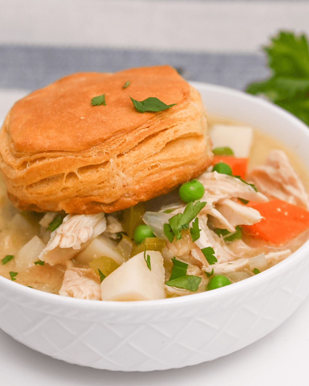 A scrumptious crock pot chicken pot pie soup with a flaky biscuit on top.