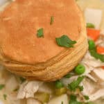 A plate of food with a biscuit and vegetables, including a crockpot chicken pot pie.