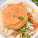 A crock pot chicken pot pie soup with a biscuit on top.