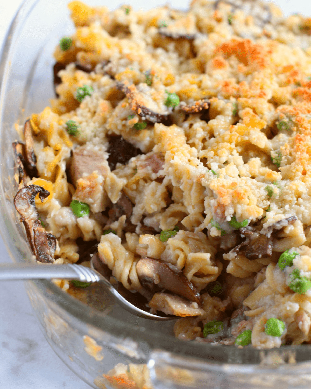 A close-up of casserole with fusilli pasta, peas, and a breadcrumb topping.