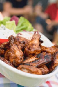 Grilled crispy chicken wings in a white serving dish.