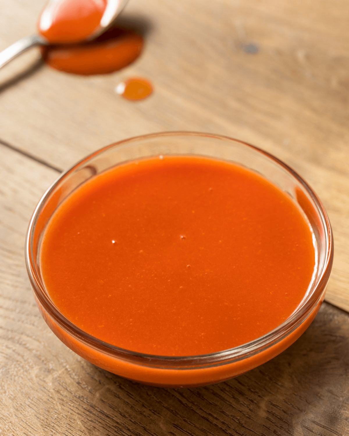 A clear glass dish of the best chicken wing sauce.