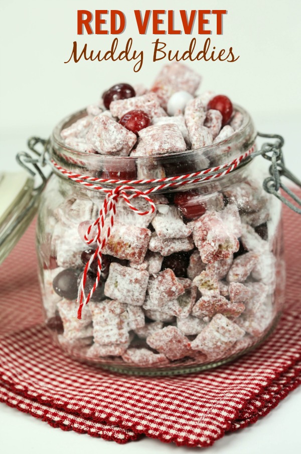 These Red Velvet Muddy Buddies in a glass jar, on top of a white and red napkin. 