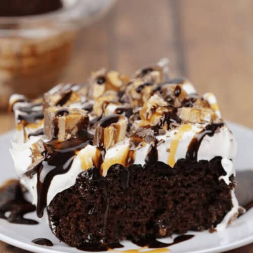 A piece of the snickers cake on a white plate.