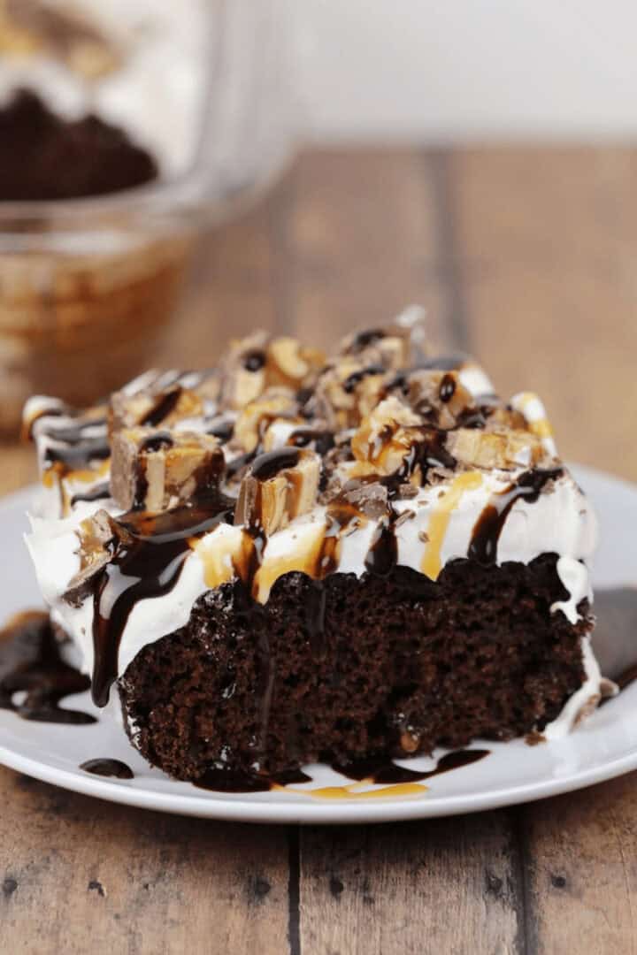 A piece of the snickers cake on a white plate.