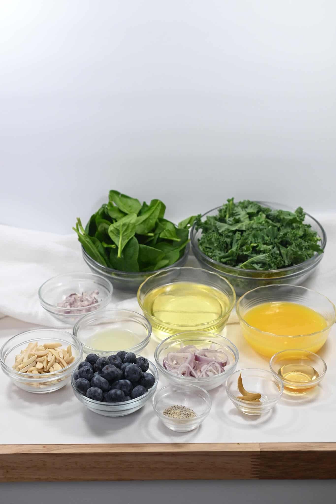 Blueberry kale and spinach salad ingredients on a white table.