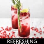 Two glasses of pomegranate cocktails garnished with rosemary and lime, with scattered pomegranate seeds on a white table.